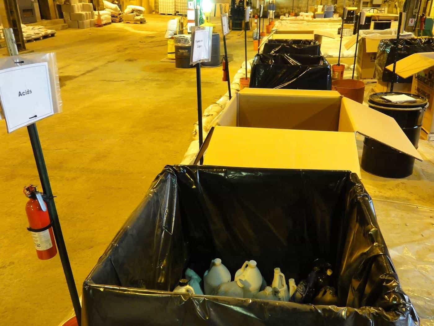 Labelled collection bins for household chemicals inside a hazardous waste drop-off facility