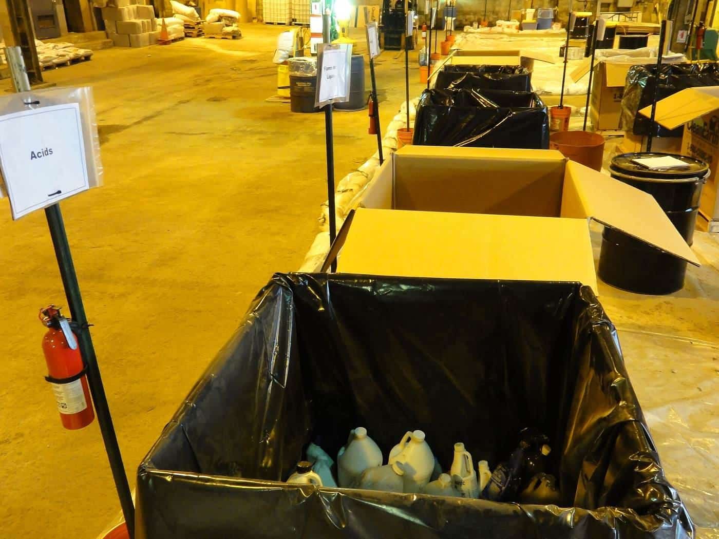 Labelled collection bins for household chemicals inside a hazardous waste drop-off facility
